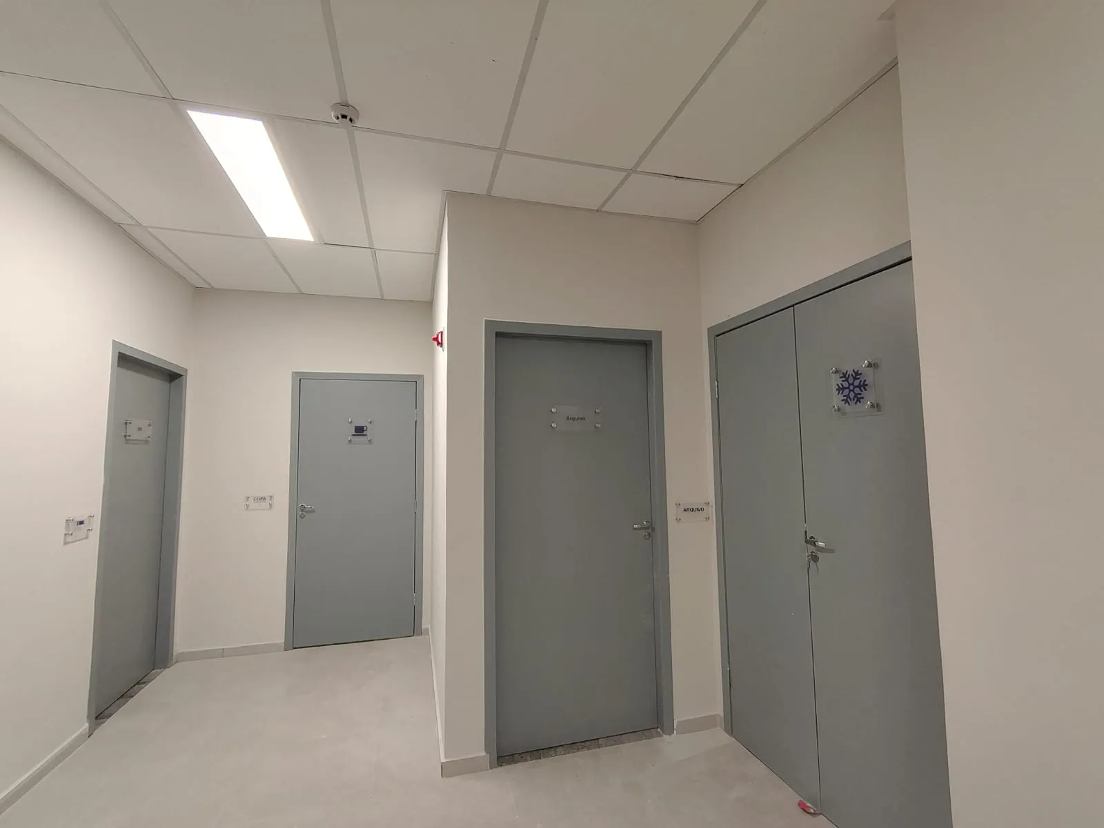 Corredor interno com portas de salas técnicas e arquivo