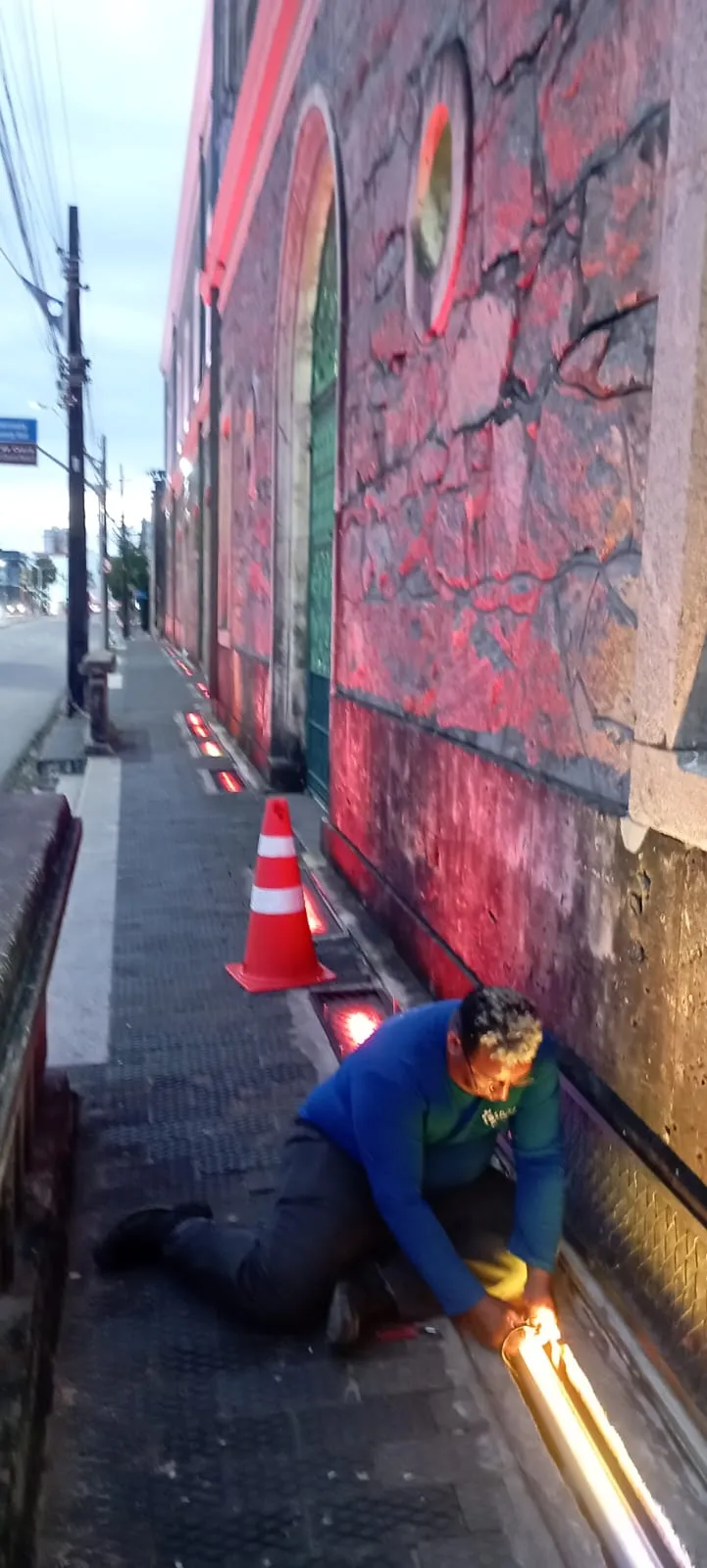 Técnico POLC instalando iluminação na fachada histórica ao entardecer