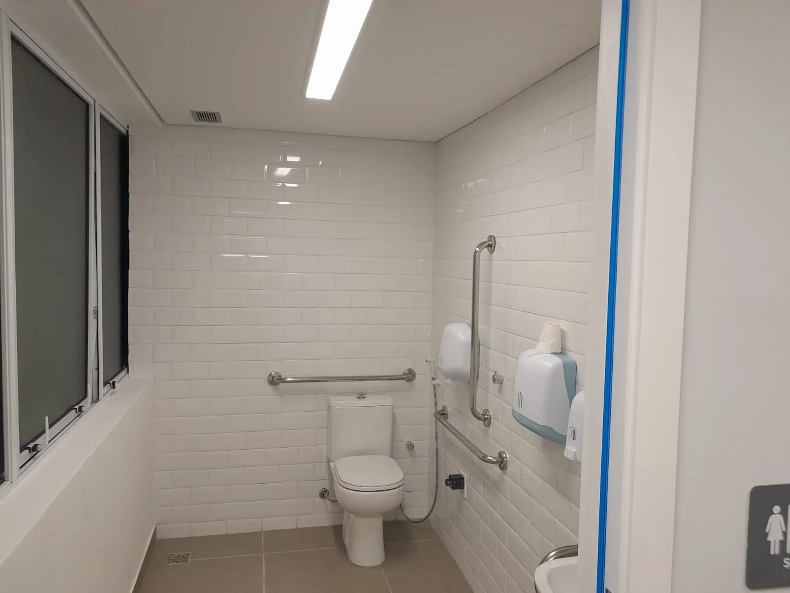 Sanitário acessível com azulejo metro branco e barras de apoio
