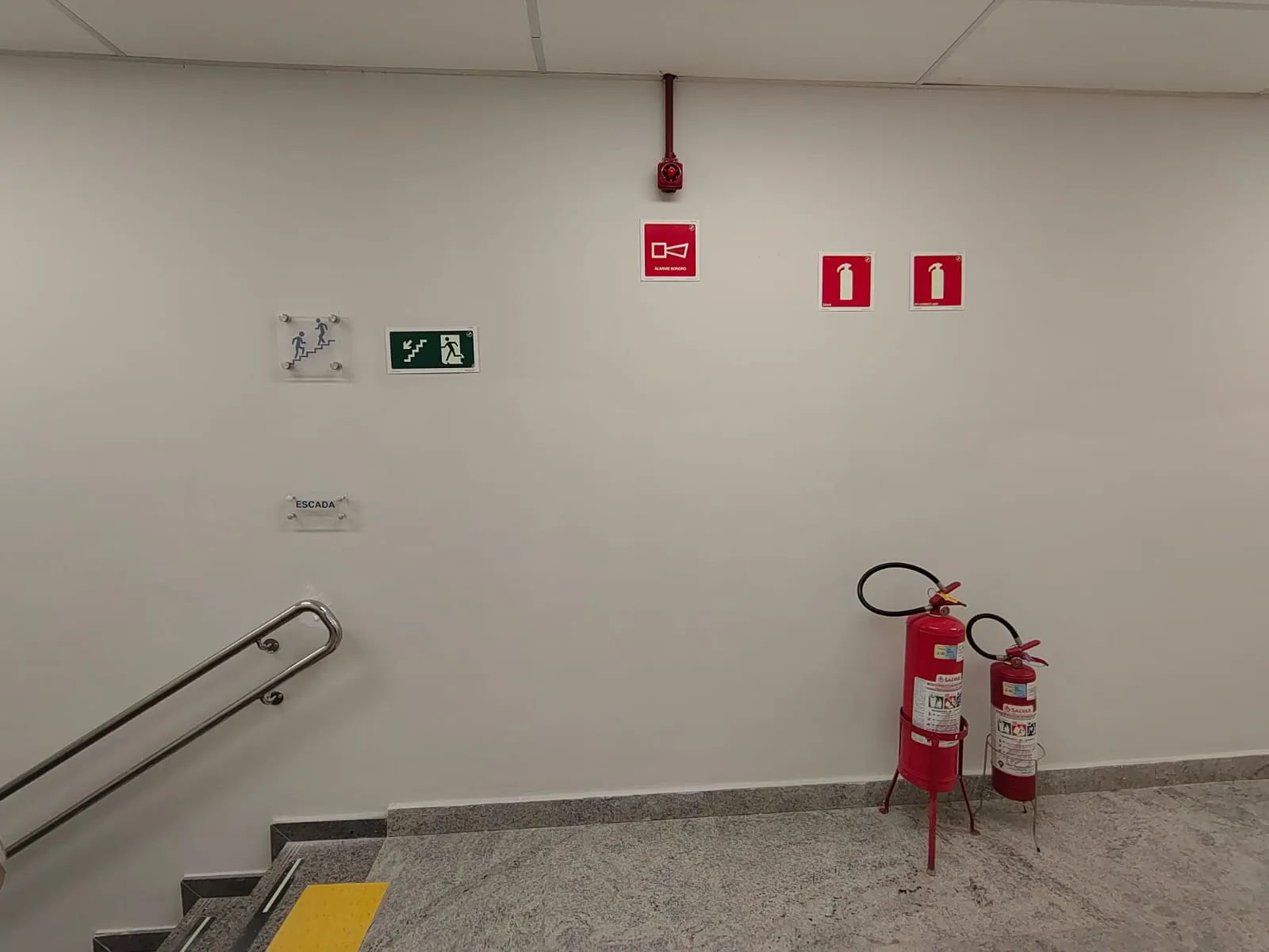 Escadaria com sinalização de emergência e extintores